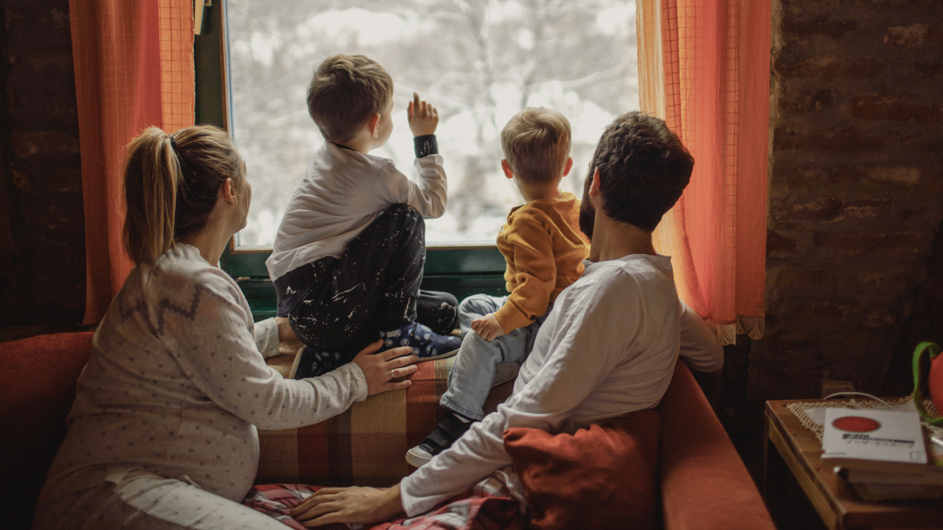 photo of a young family looking out the window at fresh snow