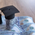 Closeup image of graduation cap and money on table.