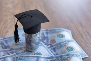 Closeup image of graduation cap and money on table.