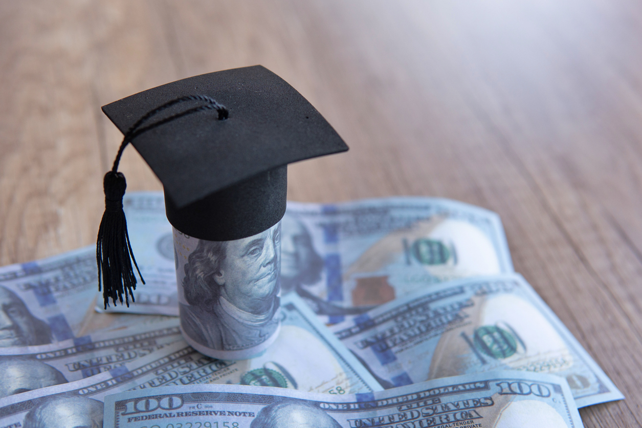 Closeup image of graduation cap and money on table.